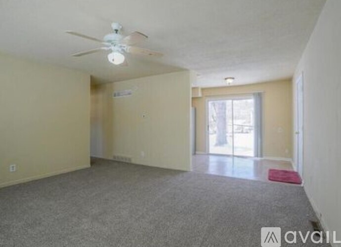 A spacious room with a ceiling fan and carpeted floor.