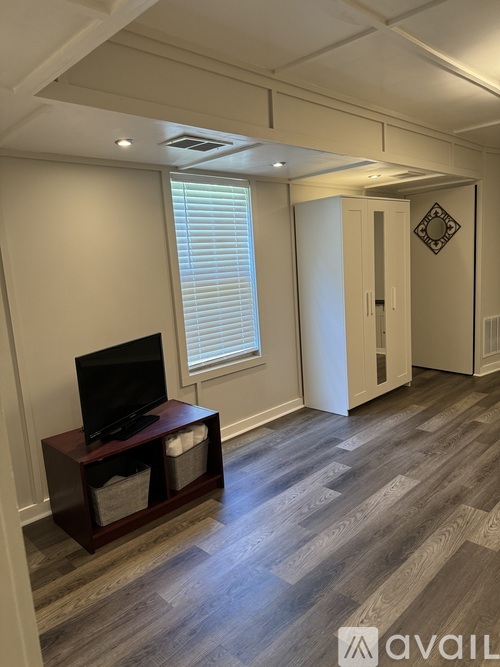 A room with a television on a stand and a doorway leading to another room.