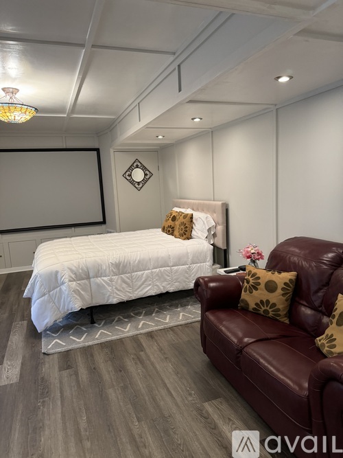 A bedroom with a white bed and a red leather couch.