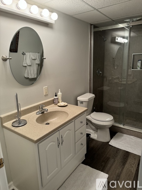A bathroom with a sink, toilet, mirror and lights.