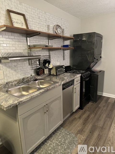 A kitchen with a black refrigerator and a marble countertop.
