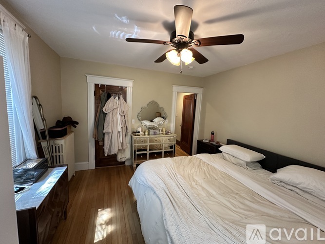 A bedroom with a bed, dresser, mirror, and a ceiling fan.