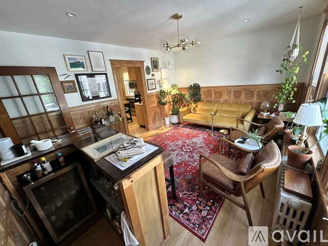 A living room with a rug on the floor and a wooden chair.