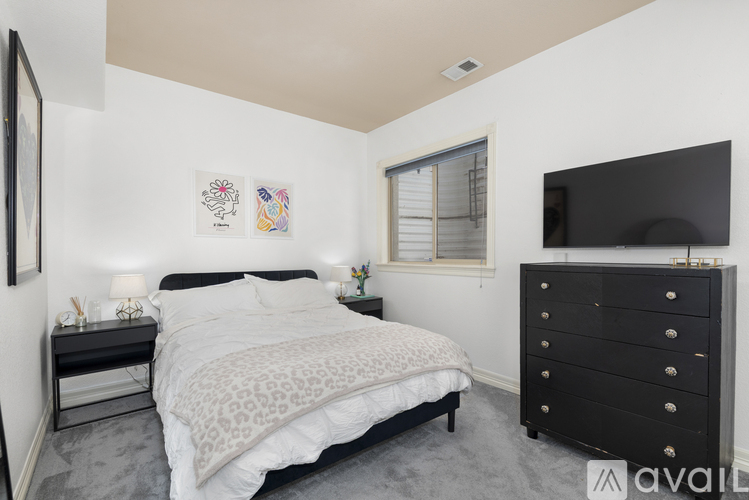 A bedroom with a large bed and a black dresser.