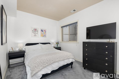 A bedroom with a large bed and a black dresser.