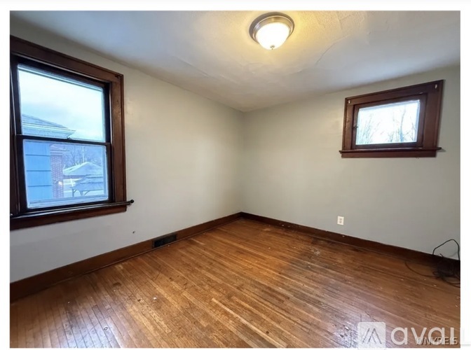 A room with wooden floors and two windows.