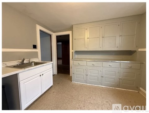 A kitchen with white cabinets and a sink.