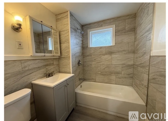 A bathroom with a tub, sink, and mirror.
