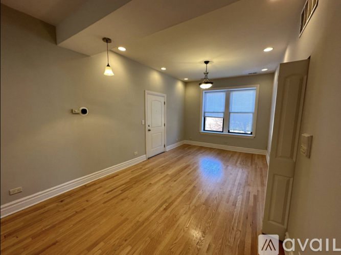 A room with wooden flooring and a window with a view of the sky.