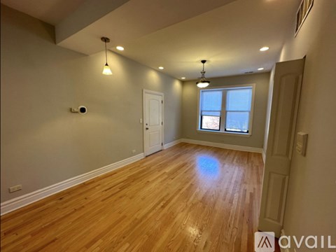 A room with wooden flooring and a window with a view of the sky.
