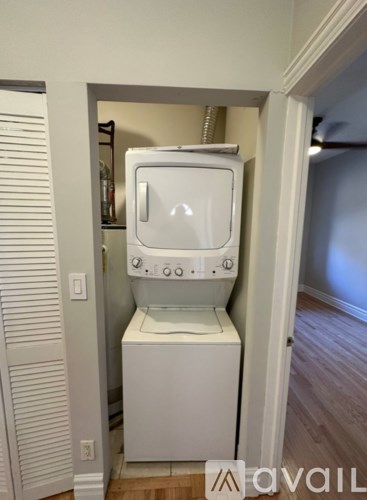 A white washing machine is in a small space between a wall and a door.