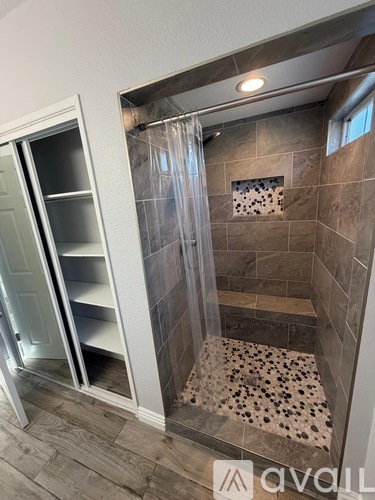 A bathroom with a walk-in shower and a white door.