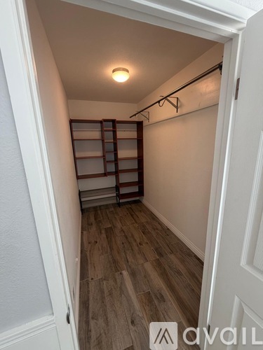 A white doorway opens to a room with a wooden floor and a wall-mounted shelf.