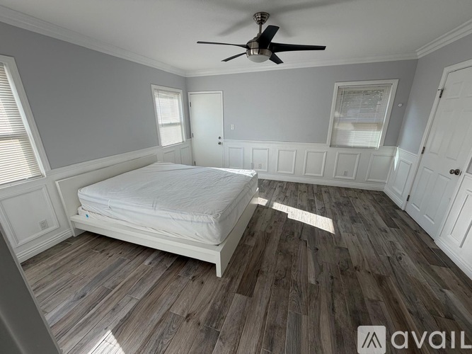 A bedroom with a bed, a ceiling fan, and wooden flooring.