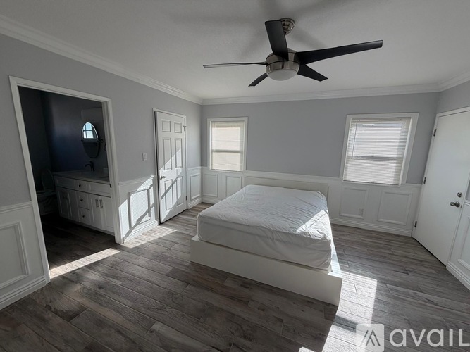 A bedroom with a bed, dresser, and ceiling fan.