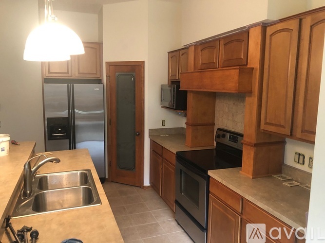 A kitchen with wooden cabinets and a stainless steel refrigerator.