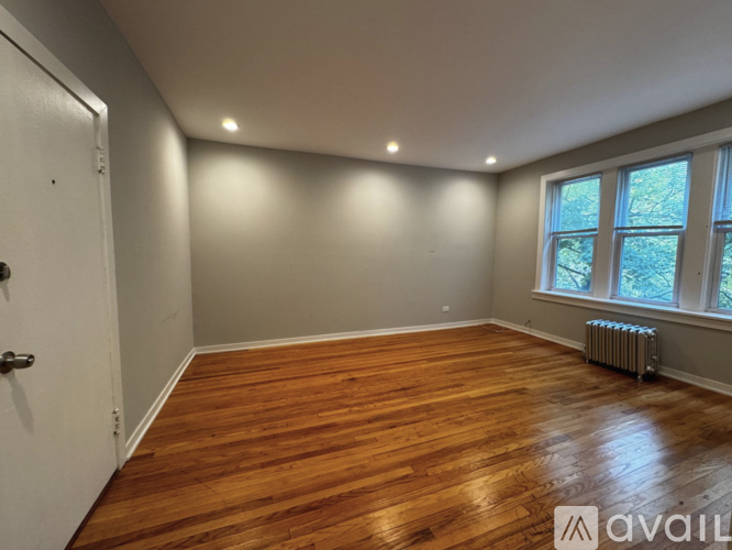 A room with wooden flooring and a window with a radiator.