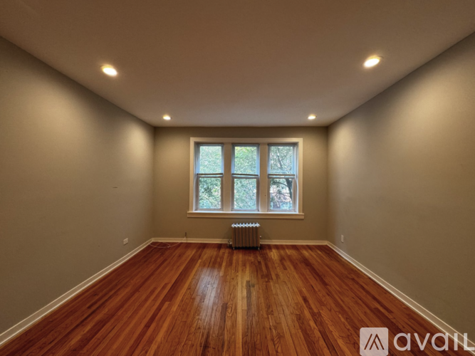 A room with wooden floors and a window with a view of trees.