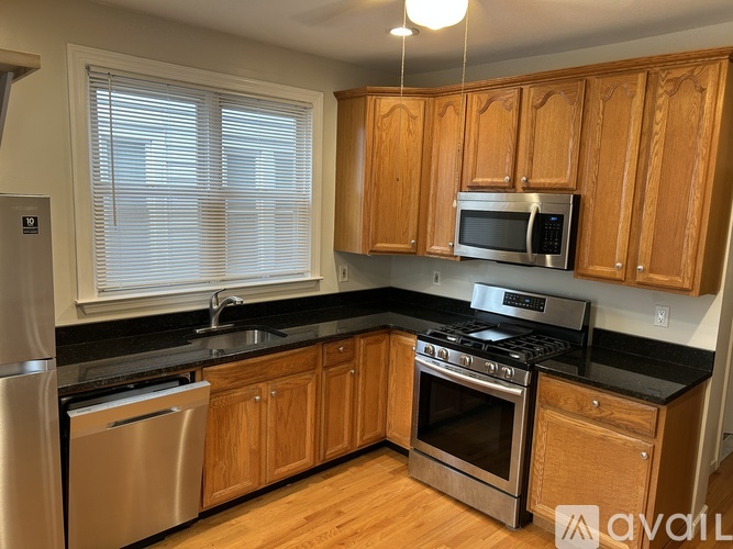 A kitchen with wooden cabinets and black countertops.