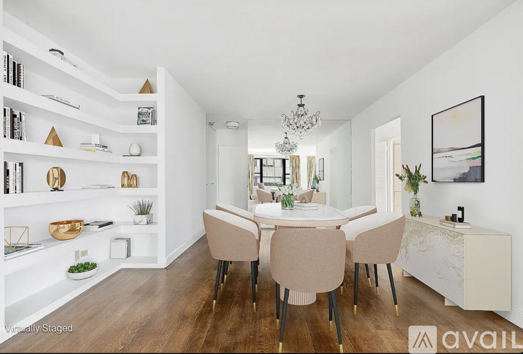 A dining room with a white table and chairs, a chandelier, and a white cabinet with a plant on top.