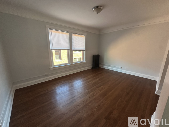 A room with wooden floors and a window with blinds.