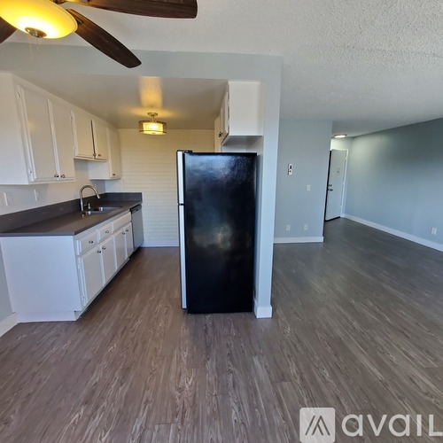 A kitchen with a black fridge and wooden floors.