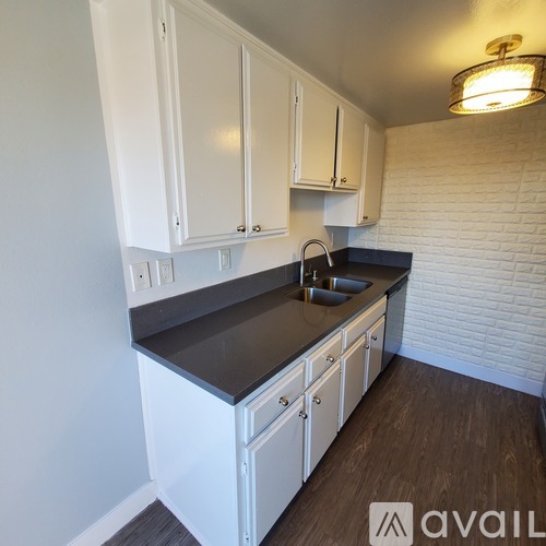A kitchen with white cabinets and a black countertop.
