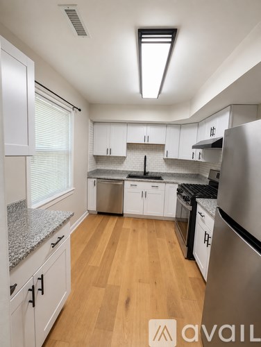 A kitchen with white cabinets and a stainless steel refrigerator.