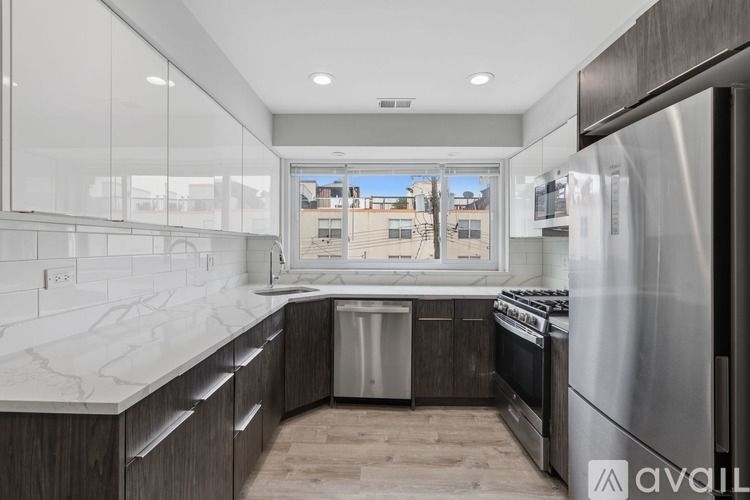 A modern kitchen with a marble countertop and stainless steel appliances.