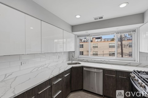 A kitchen with white cabinets and a marble countertop.