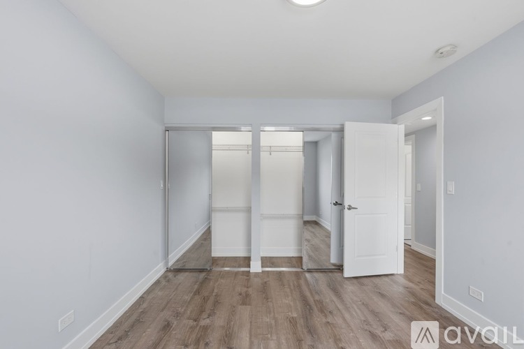 A room with a white door and a wooden floor.