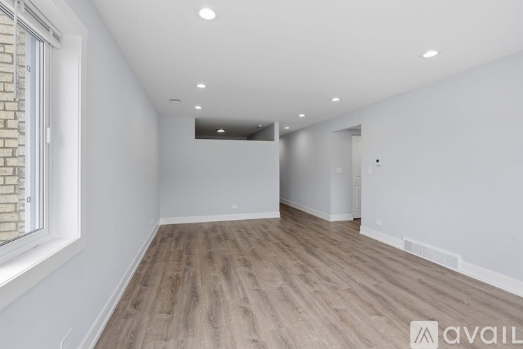 A spacious room with wooden flooring and white walls.