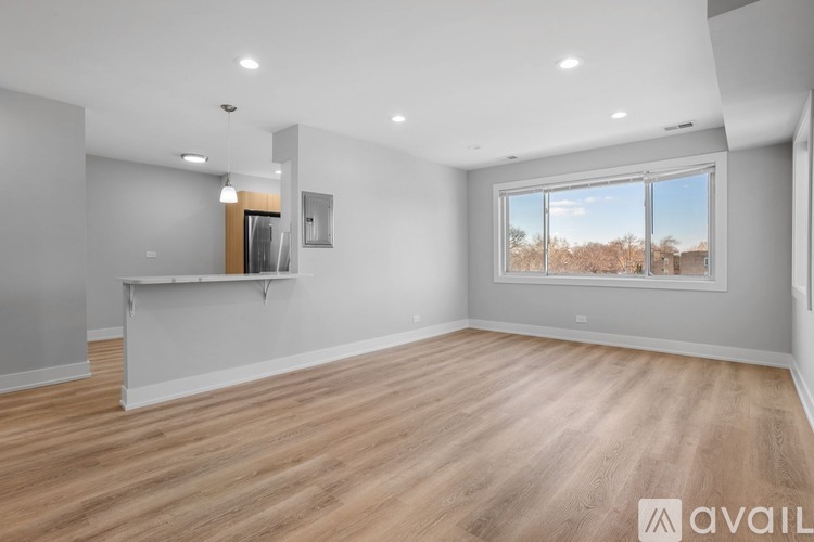 A spacious room with wooden flooring and a large window.