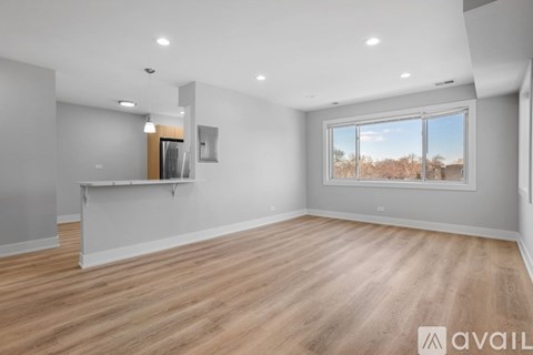 A spacious room with wooden flooring and a large window.