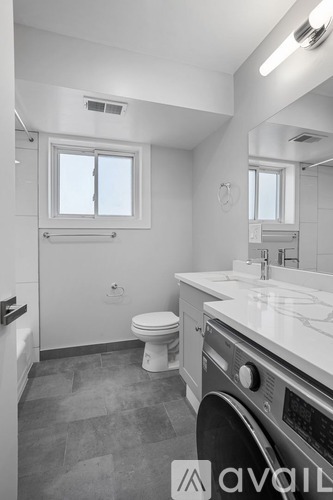 A bathroom with a toilet, sink, and window.