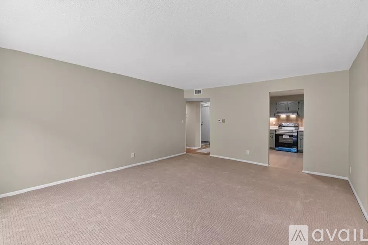 A spacious room with a carpeted floor and a doorway leading to another room.