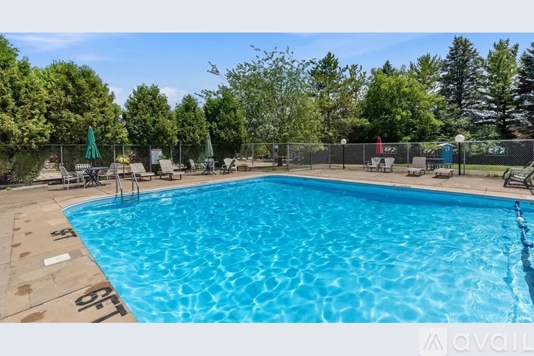 A large outdoor swimming pool surrounded by trees and lounge chairs.