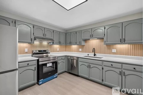 A kitchen with grey cabinets and a white refrigerator.