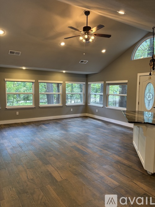 A spacious room with a ceiling fan and large windows.