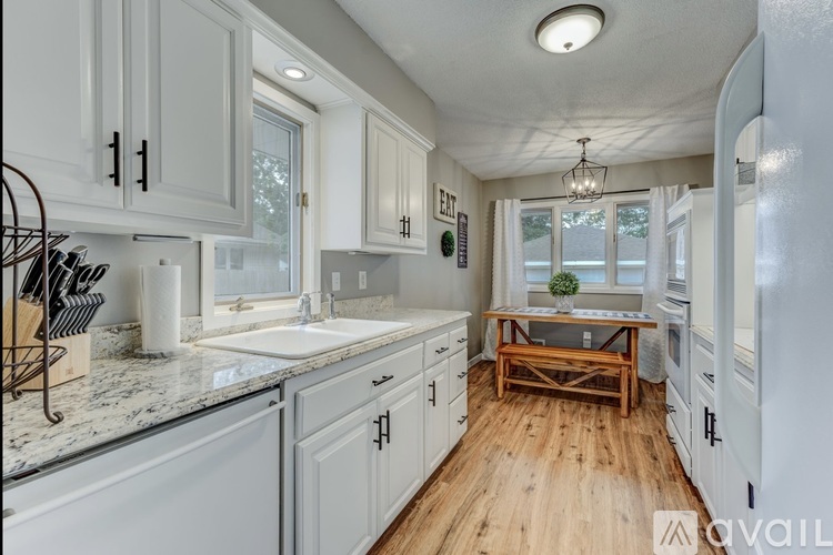 A kitchen with white cabinets and a wooden floor.