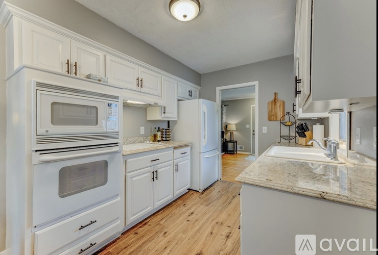 A kitchen with white cabinets and a marble countertop.
