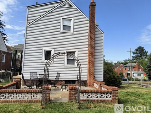 A house with a white siding and a brick chimney is for sale.
