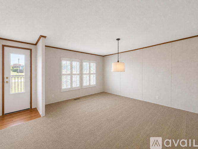 A spacious room with a door, a window, and a hanging light fixture.