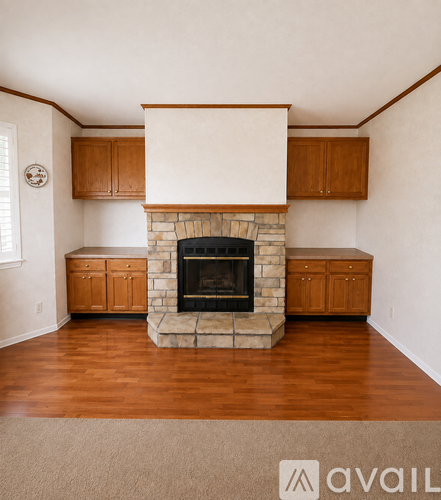 A living room with a stone fireplace and wooden cabinets.