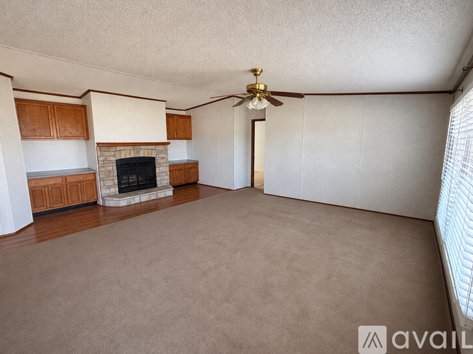 A living room with a fireplace and a ceiling fan.