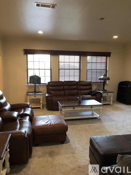 A living room with brown leather furniture and a large window.