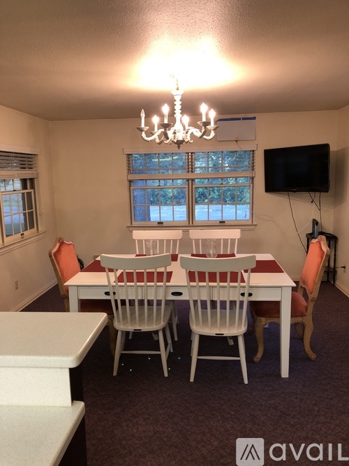 A dining room with a white table and chairs.