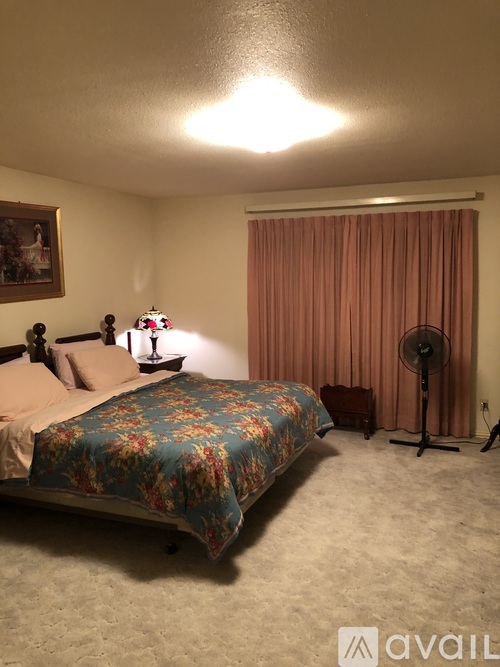 A bedroom with a floral bedspread and a fan.