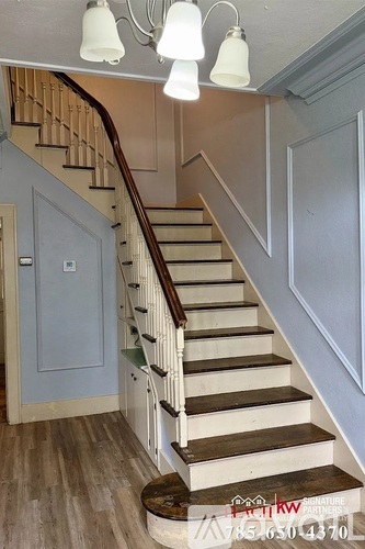 A staircase with a wooden handrail and white steps.