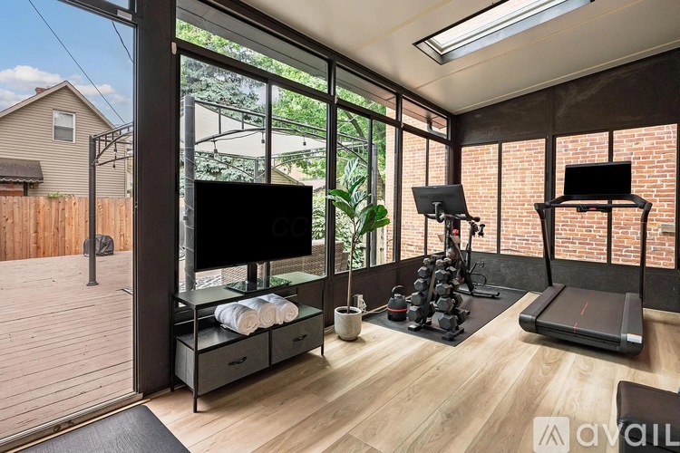 A home gym with a treadmill, weights, and exercise equipment.